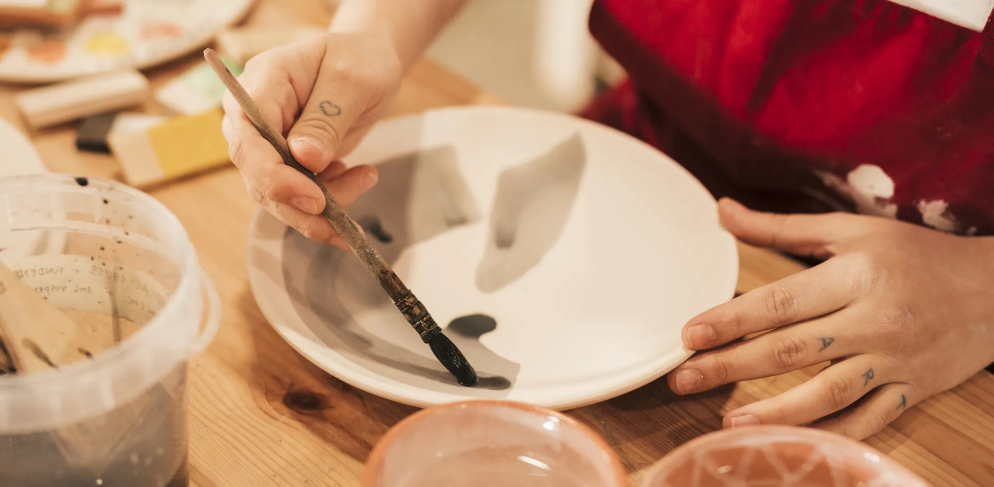 Keramikstudio: gedeckter Maltisch mit Pinseln und Tassen